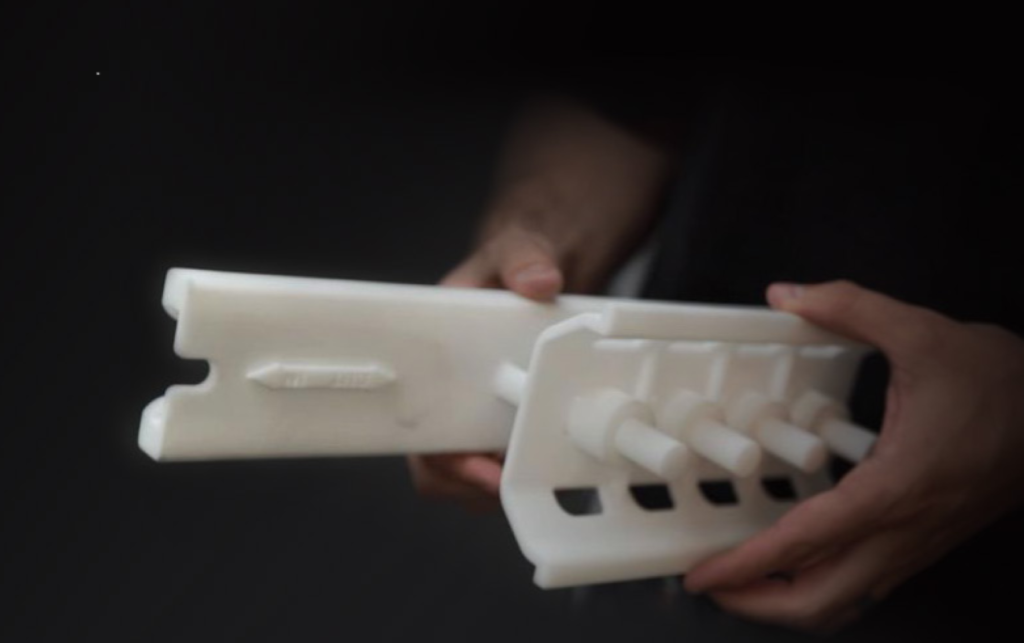 3D SLS production printing with selective laser sintering for short-run manufacturing, featuring a white prototype part held between fingers