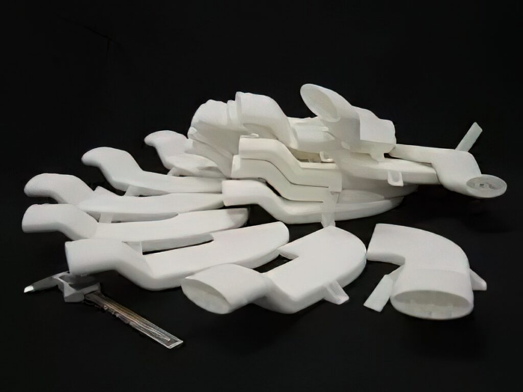 A collection of white 3D-printed parts on a black background with a measurement tool.