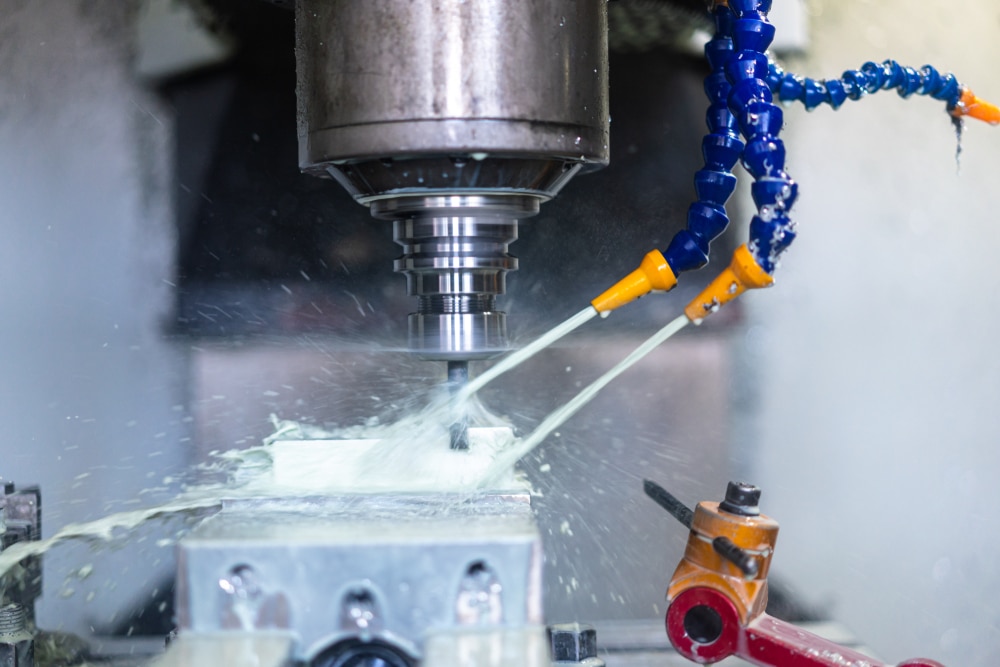 Close-up of a CNC machine performing precision cutting with coolant spraying on the material.