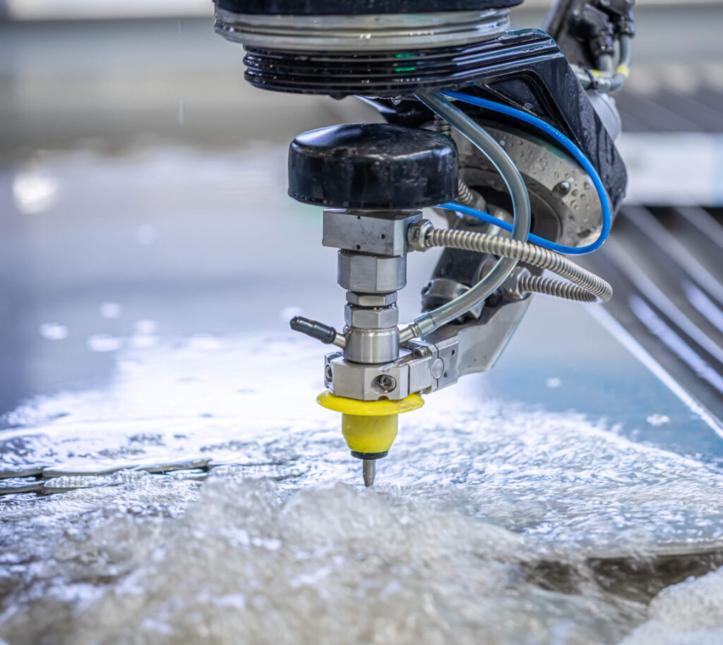 Close-up of a water jet cutter in action, showcasing precision cutting in a pool of water.