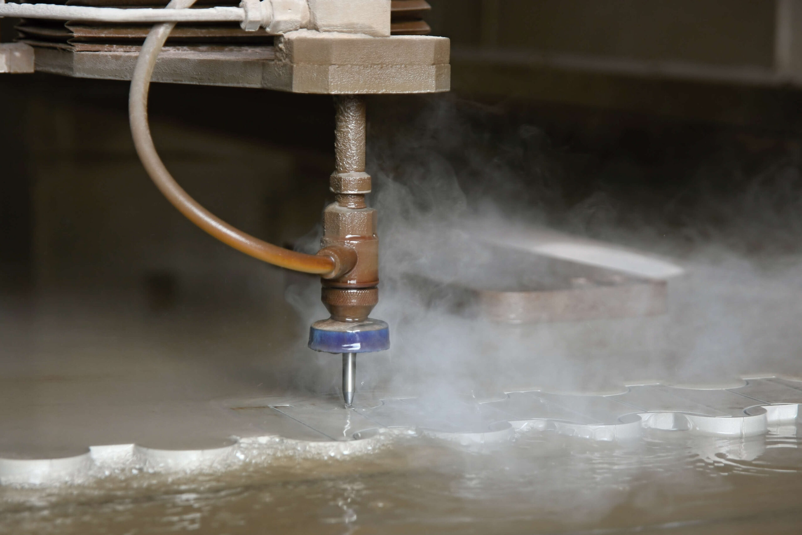 Close-up of a water jet cutting machine precision-cutting patterns on a metal sheet.