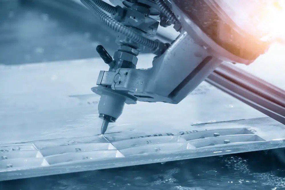 Close-up of a waterjet cutter creating precise cuts in a sheet of material.