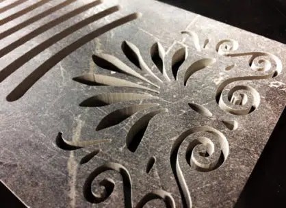 Decorative metal panel with intricate floral and swirl patterns cut with precision, showcasing fine craftsmanship and detail.