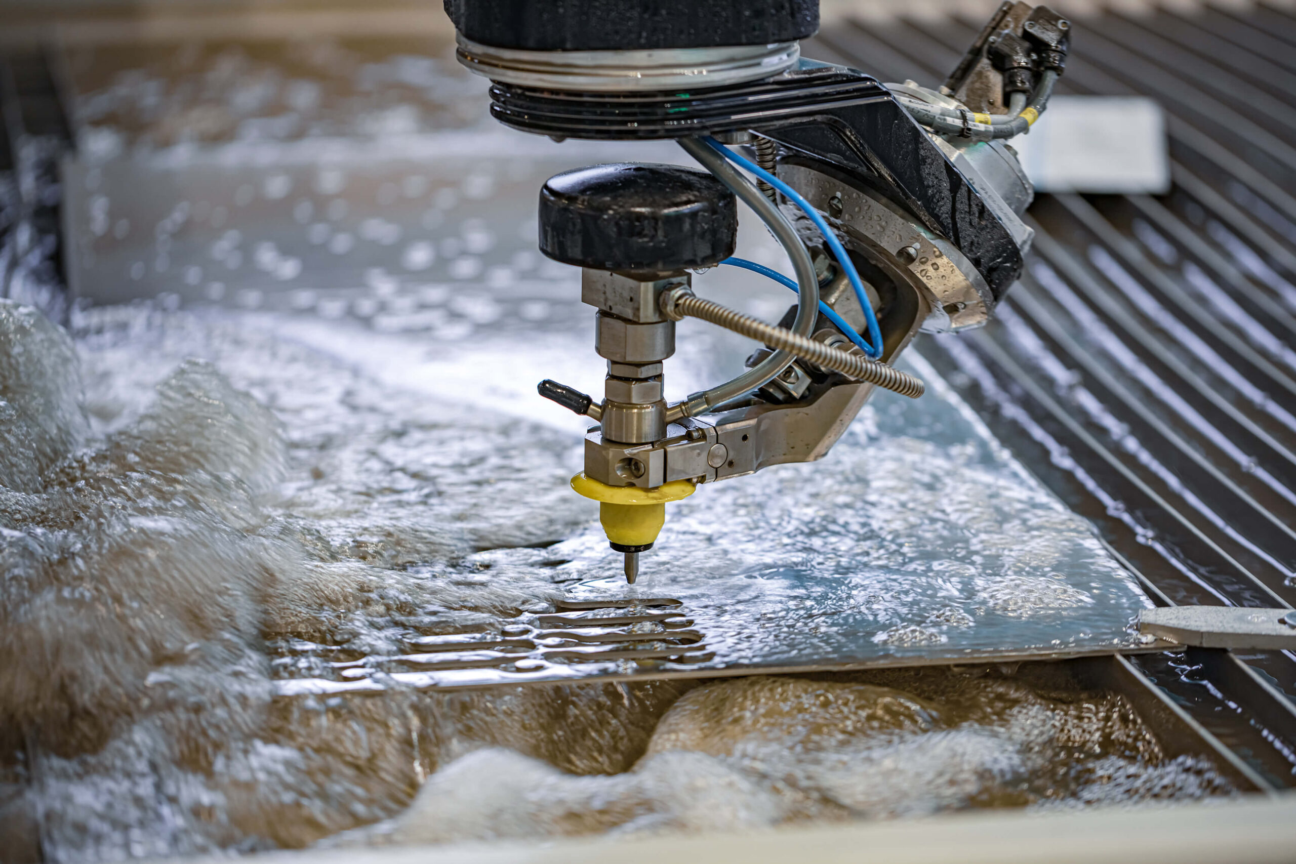 Focused view of a water jet cutter precisely slicing through a sheet of metal with high-pressure water, emphasizing precision